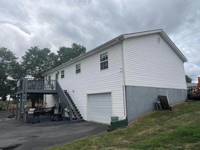 view of side of home with an attached garage, stairway, and a wooden deck