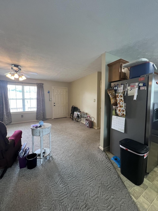 living room featuring light carpet, ceiling fan, and a textured ceiling