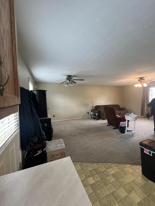 living area featuring light carpet, ceiling fan, and a textured ceiling