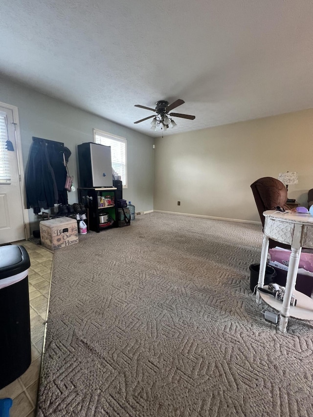 living room with ceiling fan, a textured ceiling, and baseboards