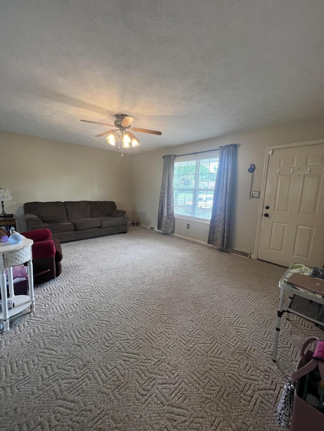 living area featuring carpet floors, ceiling fan, visible vents, and a textured ceiling