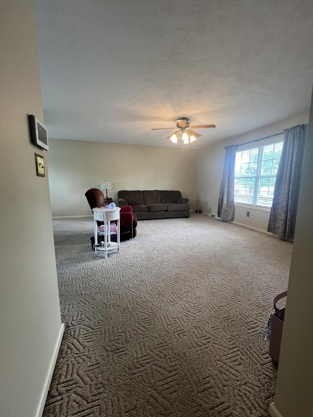 unfurnished living room with carpet floors, ceiling fan, baseboards, and a textured ceiling