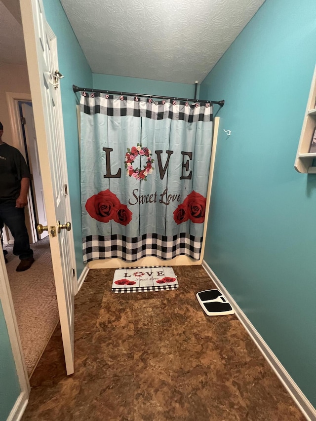 full bathroom with baseboards, a textured ceiling, and a shower with shower curtain