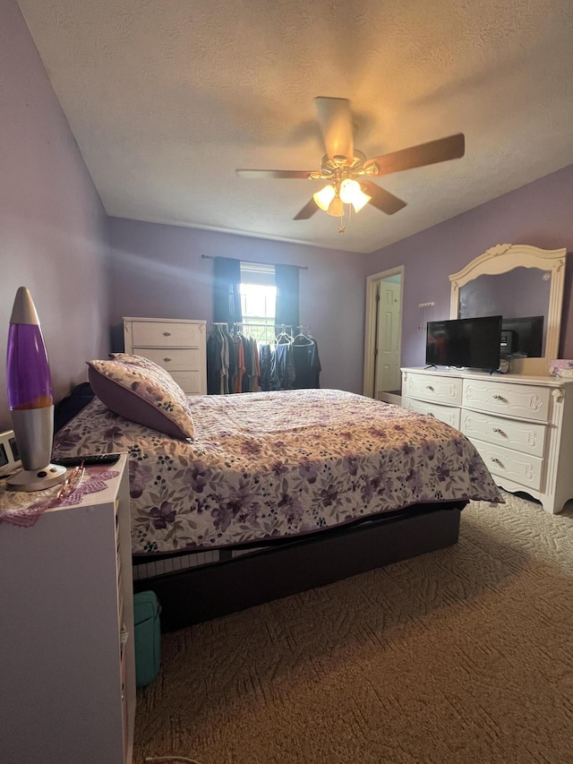 carpeted bedroom featuring a textured ceiling and a ceiling fan