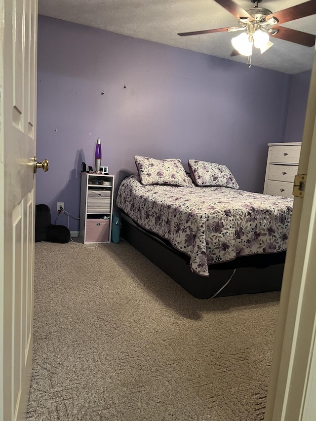 carpeted bedroom featuring a ceiling fan and a textured ceiling