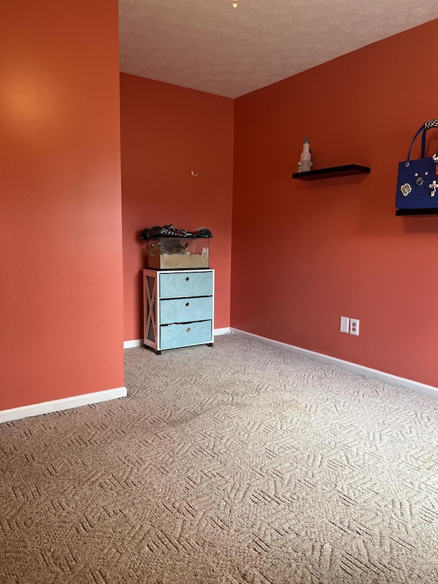 carpeted empty room featuring baseboards and a textured ceiling