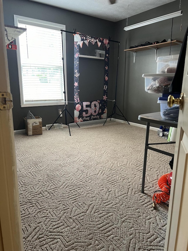 carpeted bedroom featuring a textured ceiling and baseboards