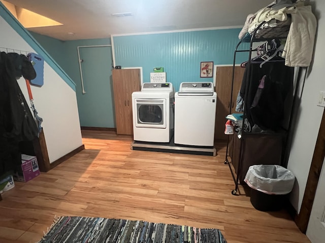 laundry area with light wood-type flooring, washing machine and dryer, and laundry area