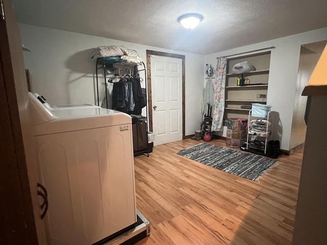 office space with built in shelves, washer / clothes dryer, light wood-style floors, a textured ceiling, and baseboards