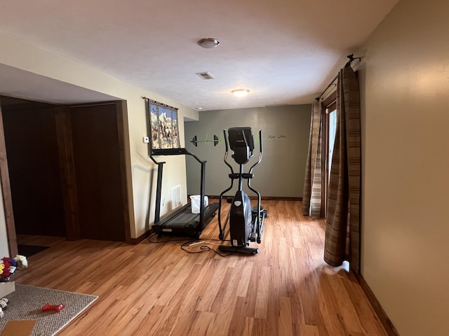 exercise room featuring light wood-type flooring, baseboards, and visible vents