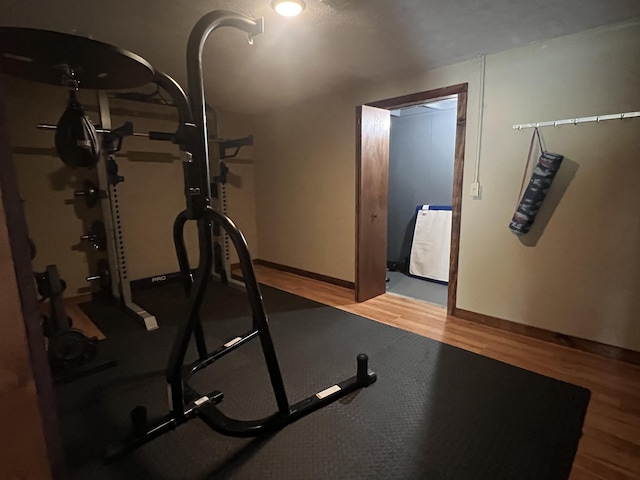 exercise area with baseboards and wood finished floors