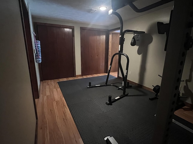 exercise room featuring light wood-type flooring and baseboards