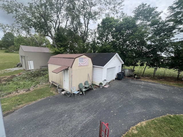 view of outdoor structure with aphalt driveway and an outbuilding