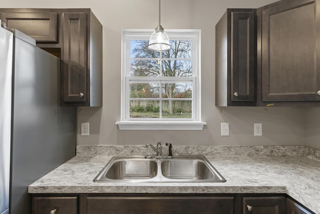 kitchen with light countertops, a sink, and dark brown cabinetry