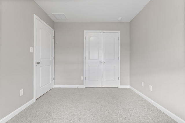 unfurnished bedroom with a closet, carpet, visible vents, and baseboards