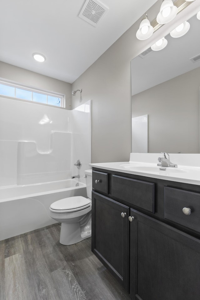 full bathroom with toilet, washtub / shower combination, visible vents, and wood finished floors