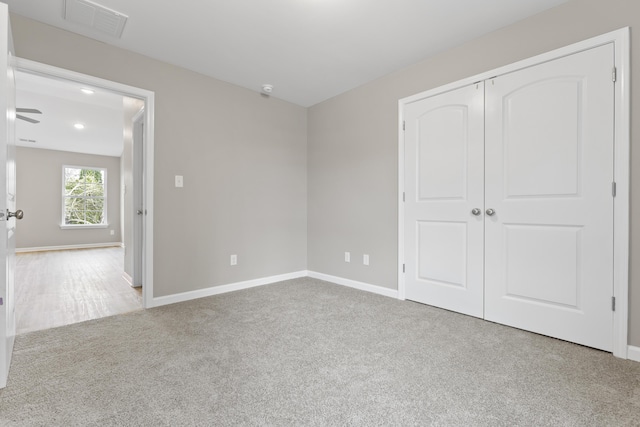 unfurnished bedroom with a closet, carpet flooring, visible vents, and baseboards