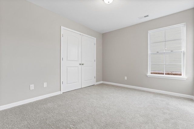 unfurnished bedroom featuring carpet, visible vents, and baseboards