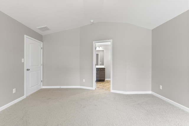 unfurnished bedroom with lofted ceiling, light colored carpet, visible vents, and baseboards