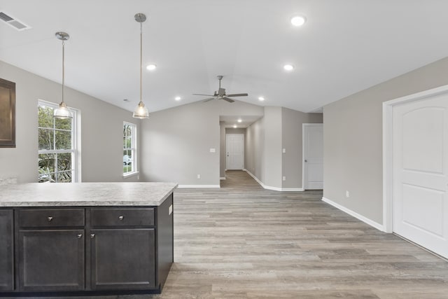 kitchen featuring light wood finished floors, lofted ceiling, visible vents, a peninsula, and baseboards