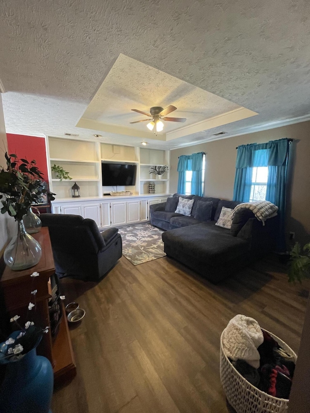 living area featuring a ceiling fan, a raised ceiling, a textured ceiling, and wood finished floors