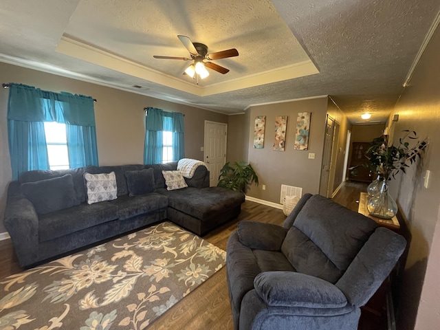 living area featuring a textured ceiling, a tray ceiling, wood finished floors, and baseboards