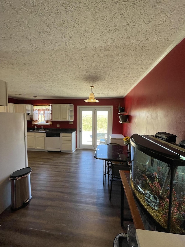 dining room with a textured ceiling, ornamental molding, and dark wood-style flooring