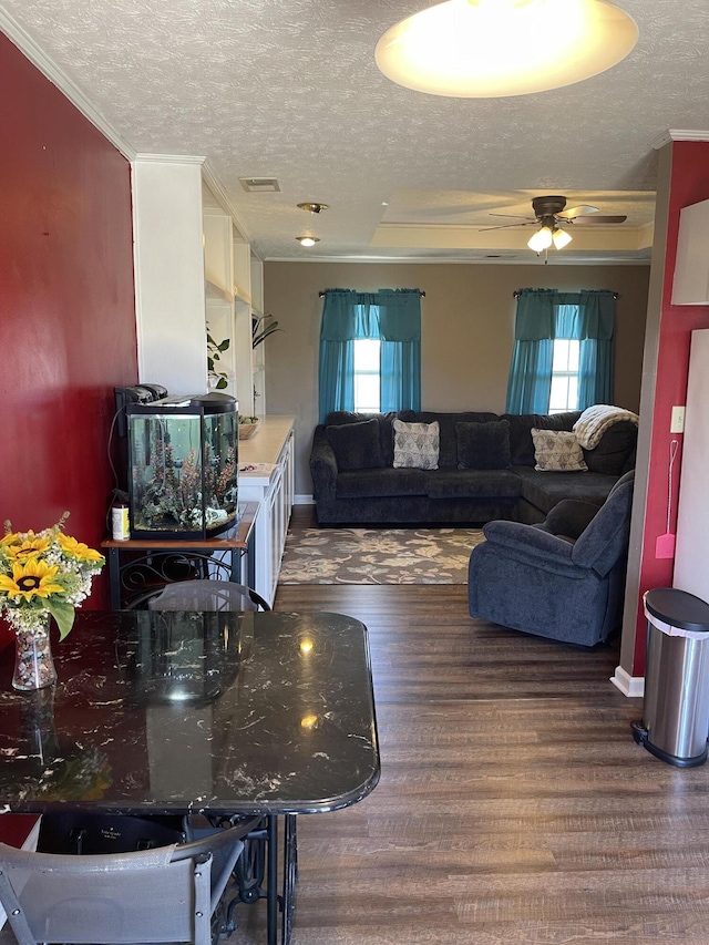 living room with baseboards, visible vents, wood finished floors, crown molding, and a textured ceiling