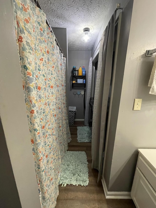 full bath featuring baseboards, wood finished floors, curtained shower, a textured ceiling, and vanity