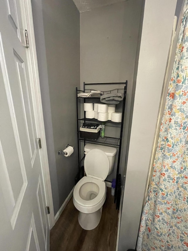 full bathroom featuring curtained shower, wood finished floors, toilet, and baseboards