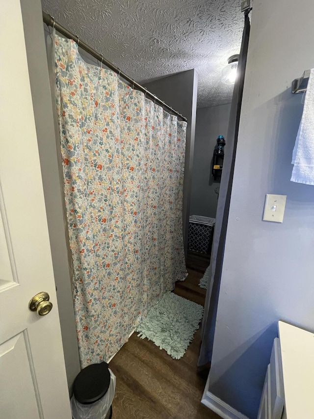 bathroom featuring a textured ceiling, a shower with shower curtain, and wood finished floors