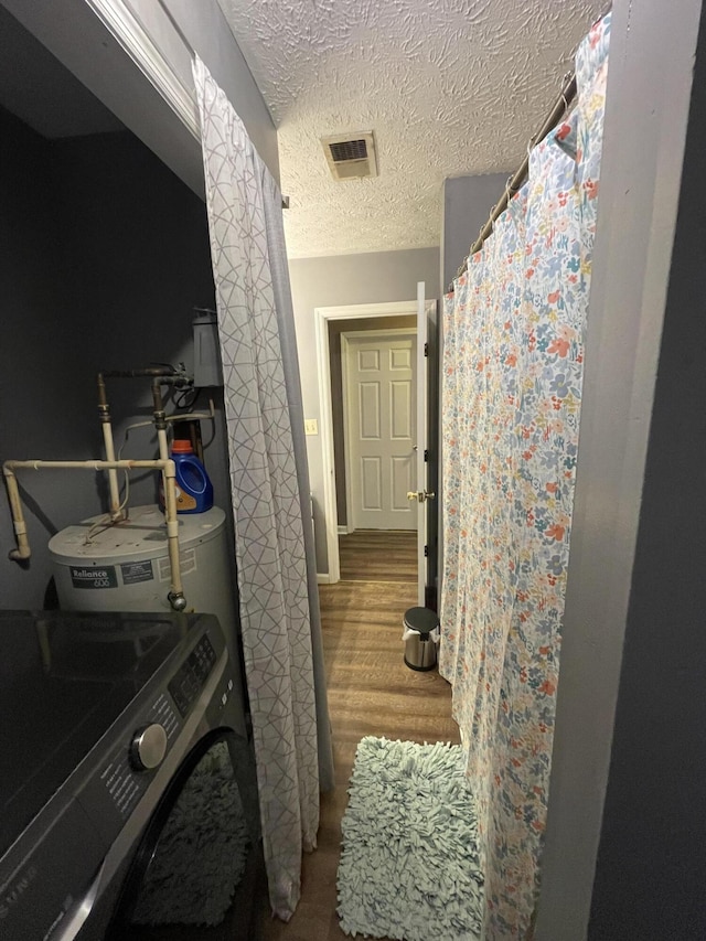 interior space with washer / dryer, a textured ceiling, visible vents, and wood finished floors