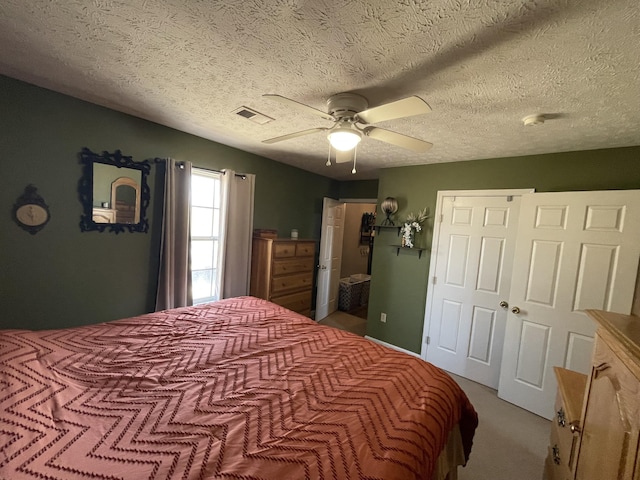 bedroom with visible vents, ceiling fan, a textured ceiling, carpet floors, and a closet