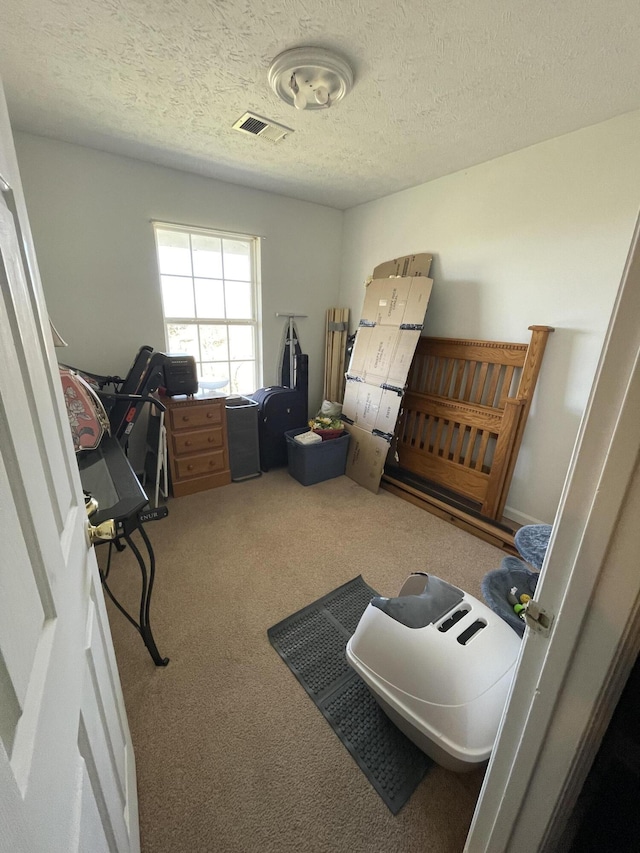 bedroom with a textured ceiling, visible vents, and carpet flooring