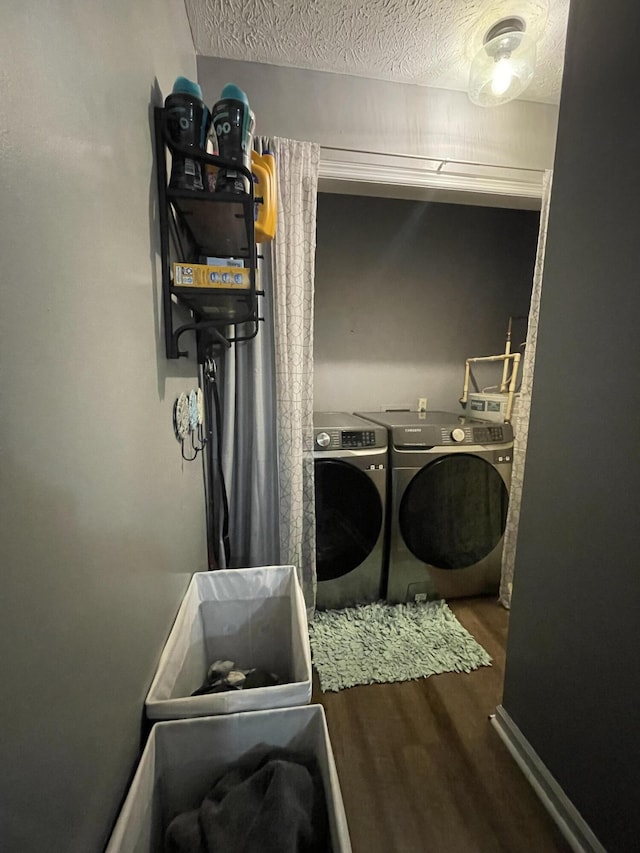 clothes washing area featuring washer and clothes dryer, a textured ceiling, wood finished floors, laundry area, and baseboards