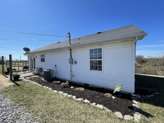 back of house featuring a shingled roof and central AC