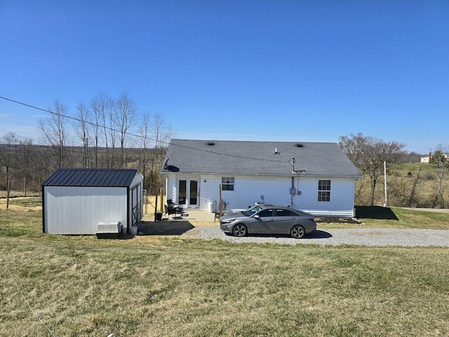 back of property with a storage unit, an outdoor structure, and a yard