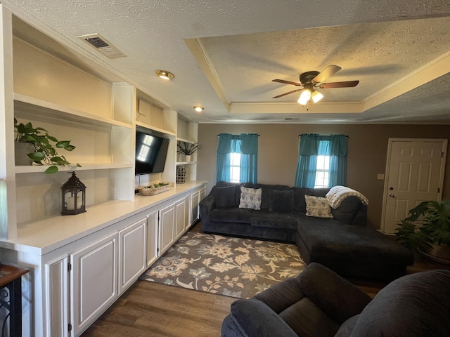 living room featuring visible vents, a raised ceiling, dark wood-style floors, ceiling fan, and a textured ceiling