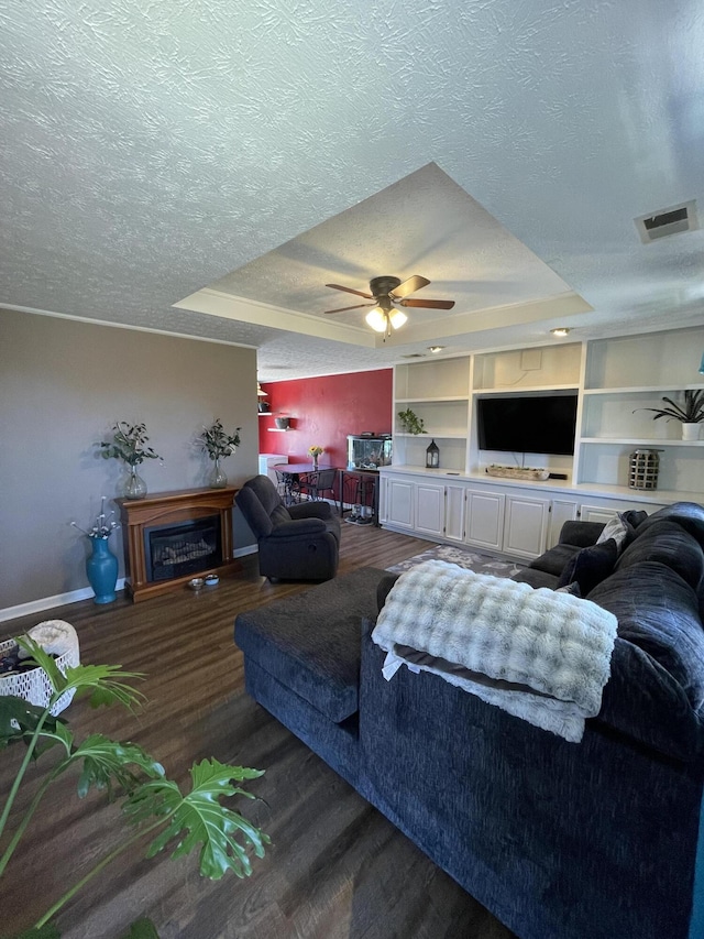 living room featuring a textured ceiling, a raised ceiling, and wood finished floors