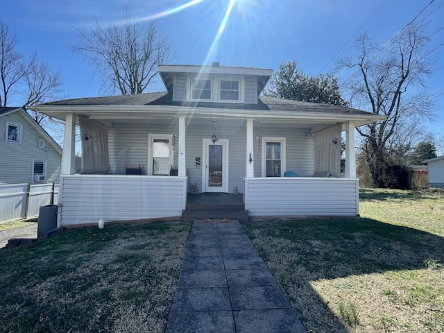 bungalow with covered porch, fence, and a front lawn