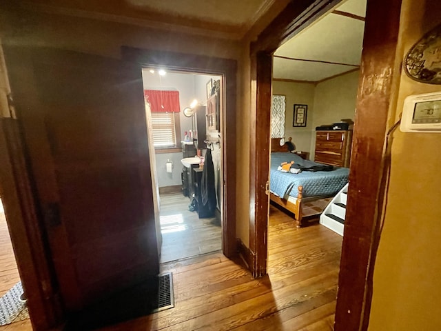 hallway with hardwood / wood-style flooring and visible vents