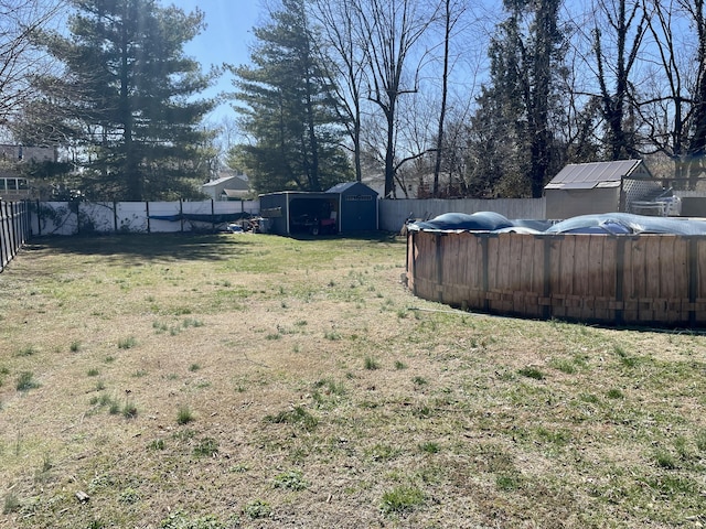 view of yard featuring a fenced in pool, a fenced backyard, an outdoor structure, and a storage unit