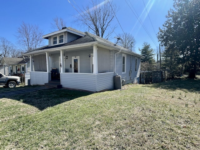 bungalow-style house with a porch, fence, and a front lawn