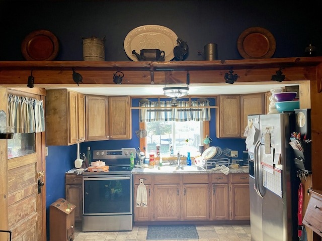 kitchen with appliances with stainless steel finishes, light countertops, brown cabinets, and a sink