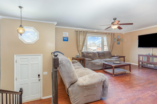 living area with a ceiling fan, wood finished floors, baseboards, and ornamental molding