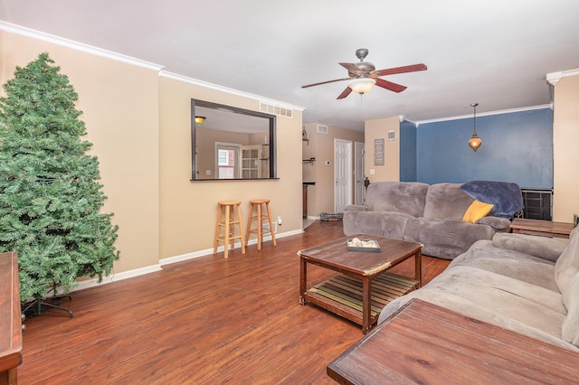 living room with ceiling fan, wood finished floors, baseboards, and ornamental molding