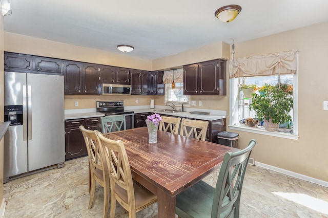 kitchen featuring a sink, stainless steel appliances, dark brown cabinetry, and light countertops