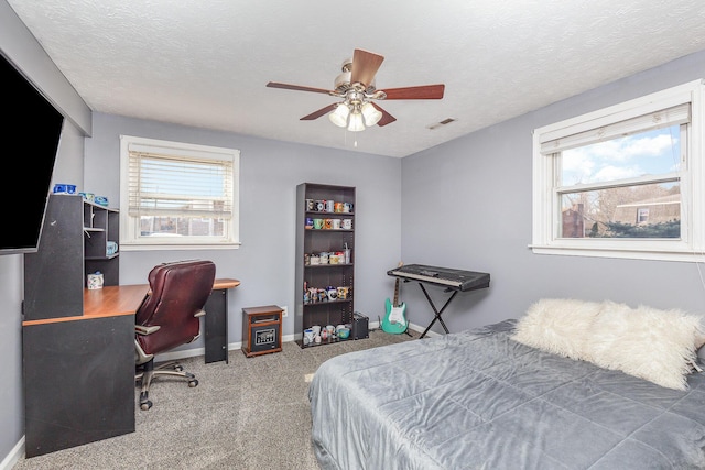 carpeted bedroom featuring visible vents, baseboards, a textured ceiling, and ceiling fan