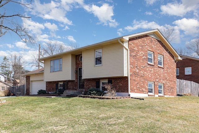 bi-level home with brick siding, an attached garage, a front yard, and fence