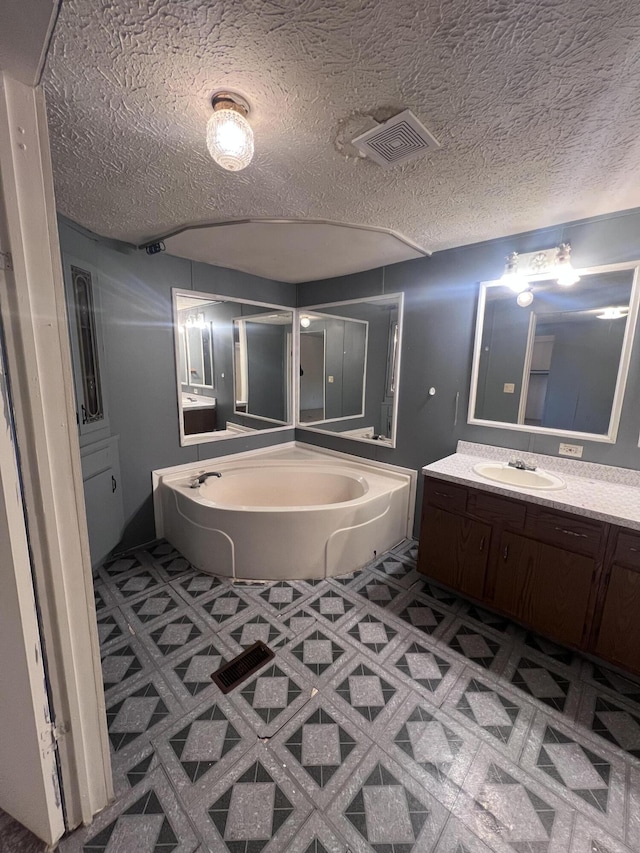 full bathroom with a bath, a textured ceiling, vanity, and visible vents